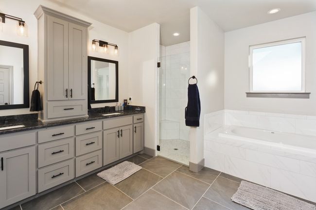 Bathroom with double vanity, a bath, a stall shower, and tile patterned flooring | Image 24