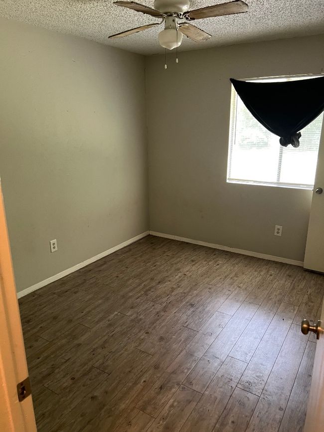 Unfurnished room featuring a ceiling fan, dark wood-style flooring, a textured ceiling, and baseboards | Image 8