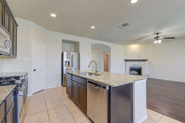 Kitchen featuring stainless steel appliances, a sink, a ceiling fan, light tile patterned floors, and arched walkways | Image 5