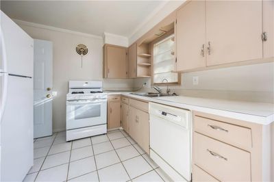 Kitchen featuring ornamental molding, sink, white appliances, and light tile patterned floors | Image 3