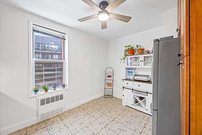 Kitchen with radiator heating unit, freestanding refrigerator, a ceiling fan, baseboards, and dark countertops | Image 9