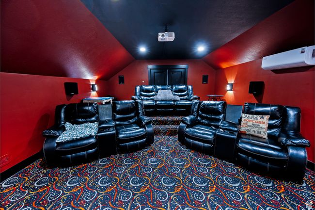 Carpeted cinema with a wall mounted AC, vaulted ceiling, and stadium seating | Image 52