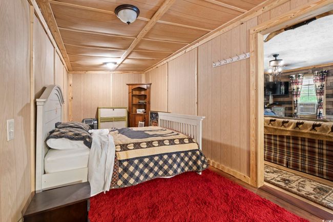 Bedroom featuring wooden walls, wood ceiling, and wood finished floors | Image 18