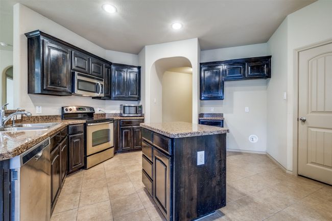 Kitchen featuring stainless steel appliances, arched walkways, a kitchen island, light tile patterned floors, and recessed lighting | Image 8