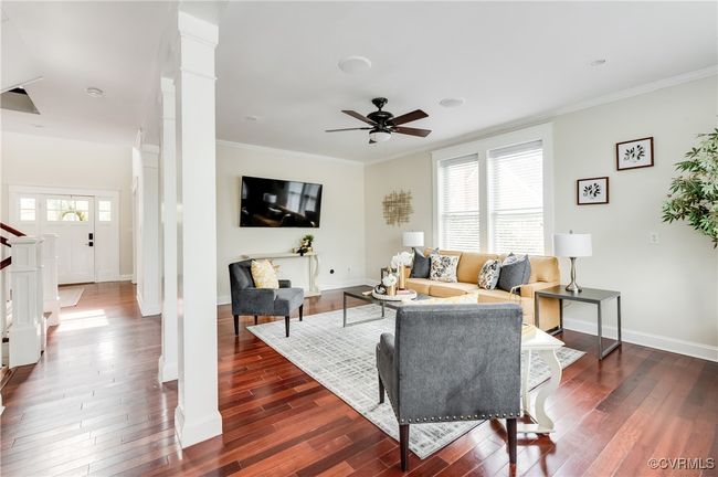 Living room featuring a ceiling fan, ornamental molding, dark wood-type flooring, and ornate columns | Image 17