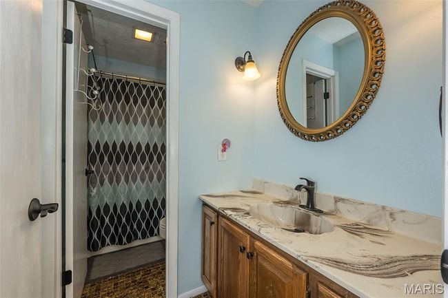 Bathroom featuring vanity, toilet, and curtained shower | Image 26