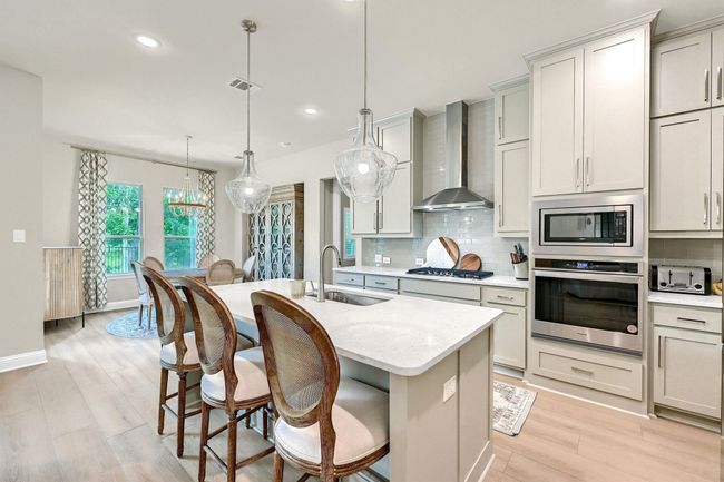 Kitchen with a sink, wall chimney exhaust hood, visible vents, appliances with stainless steel finishes, and decorative backsplash | Image 16