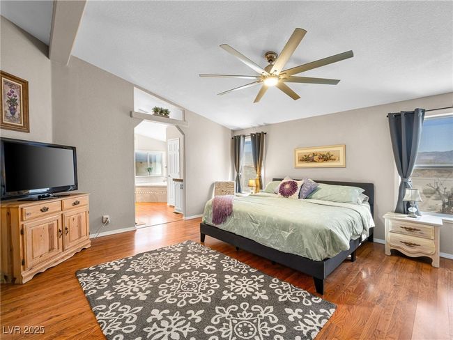 Bedroom with ensuite bath, vaulted ceiling, baseboards, and light wood-type flooring | Image 28