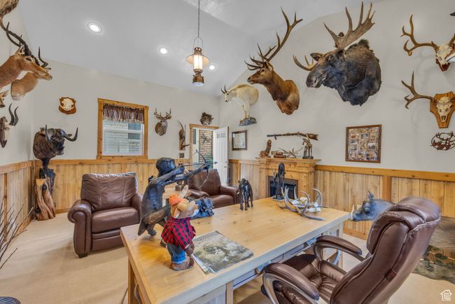 Trophy/bonus room built next to garage. Carpeted room featuring a wainscoted wall, vaulted ceiling, a high end fireplace, wood walls, and recessed lighting | Image 45