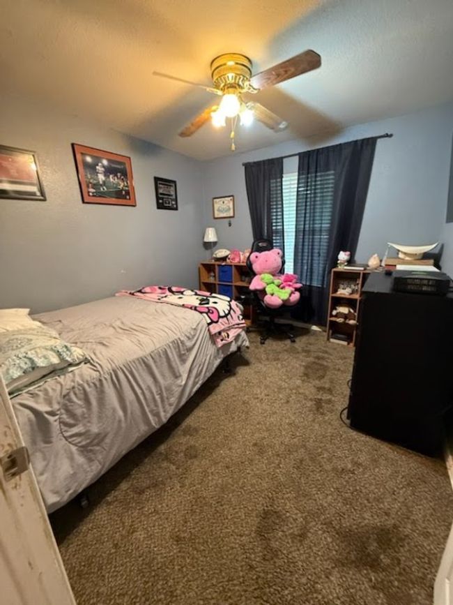 Carpeted bedroom with a textured ceiling and ceiling fan | Image 5