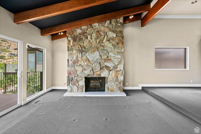 Unfurnished living room featuring beamed ceiling, a fireplace, and carpet floors | Image 8