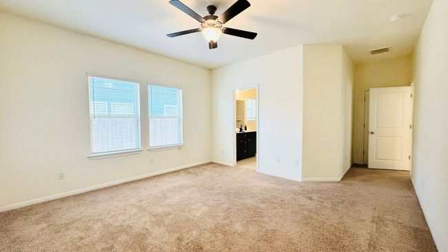 Unfurnished bedroom featuring light colored carpet, ensuite bath, and a ceiling fan | Image 21