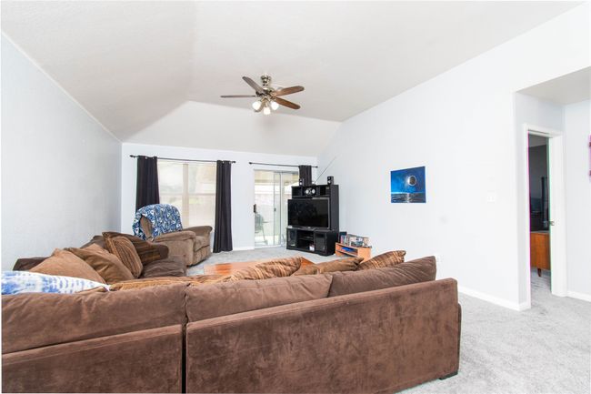 Living room with baseboards, carpet, vaulted ceiling, and a ceiling fan | Image 4