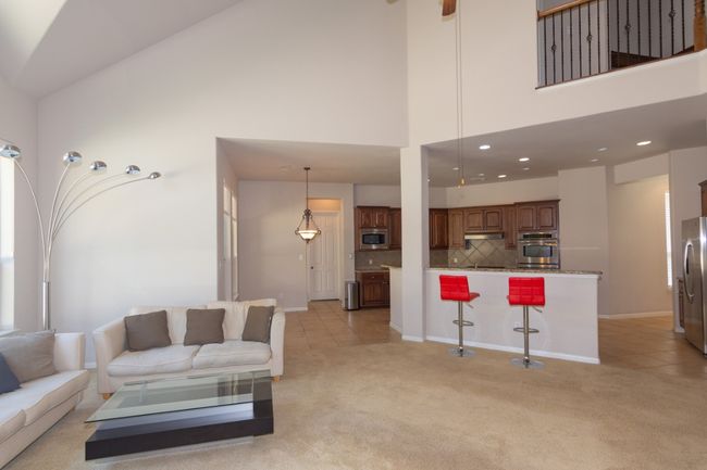 Living area featuring baseboards, a high ceiling, and light carpet | Image 6