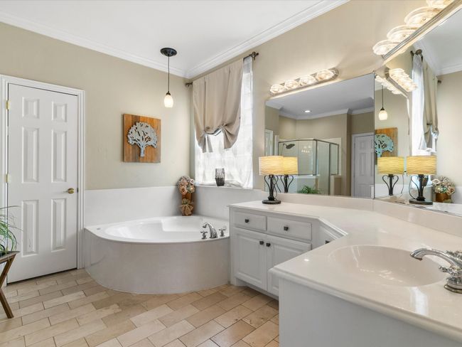 Bathroom with a stall shower, a garden tub, vanity, and crown molding | Image 22