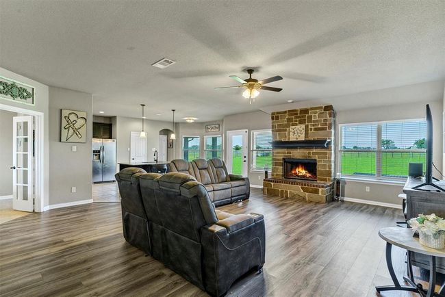 Living room with ceiling fan, a textured ceiling, hardwood / wood-style flooring, and a fireplace | Image 7