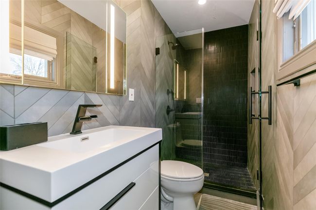 Full bathroom featuring tile walls, a shower stall, toilet, and vanity | Image 15