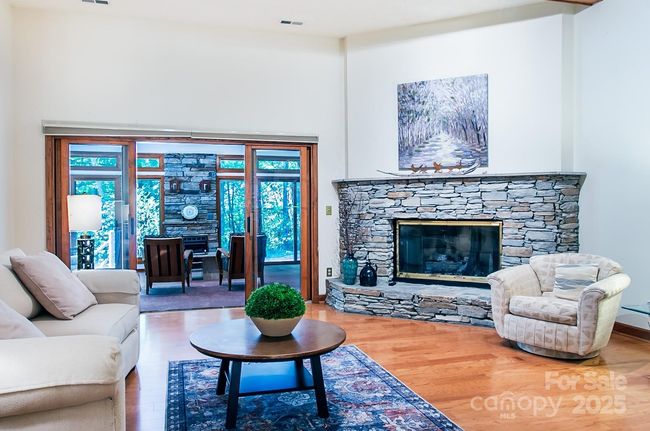 Warm and cozy living room leads to the four seasons sunroom | Image 5