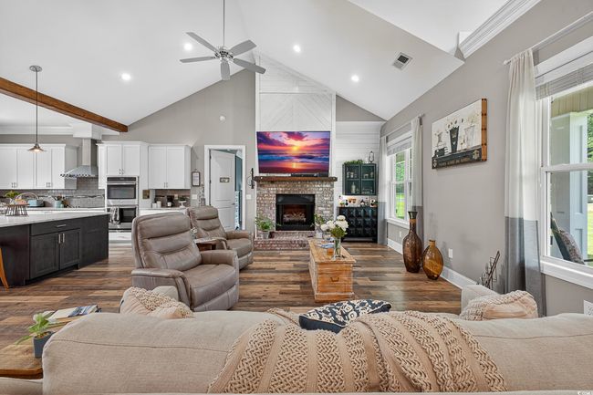Living area featuring high vaulted ceiling, dark wood-type flooring, a ceiling fan, a fireplace, and recessed lighting | Image 8