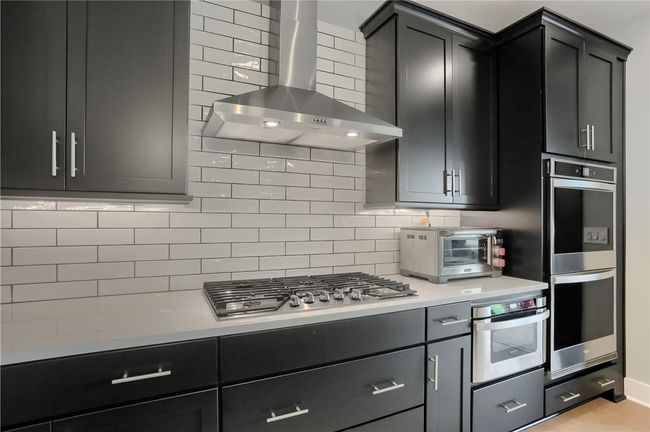 Sleek black cabinetry, stainless appliances, a gas cooktop, and crisp subway tile—this space is pure modern magic. | Image 8
