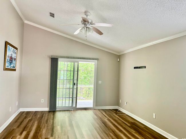 Empty room featuring a textured ceiling, wood finished floors, a ceiling fan, and lofted ceiling | Image 6