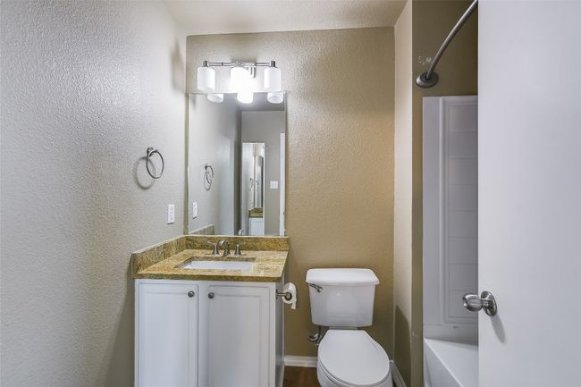 Full bathroom featuring vanity, toilet, a textured wall, and shower / washtub combination | Image 13