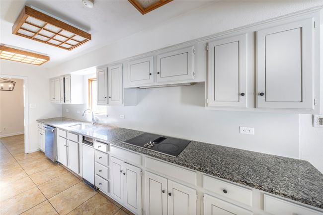 Kitchen featuring granite counter tops, floors, black electric cooktop, dishwasher, and garbage disposal | Image 11