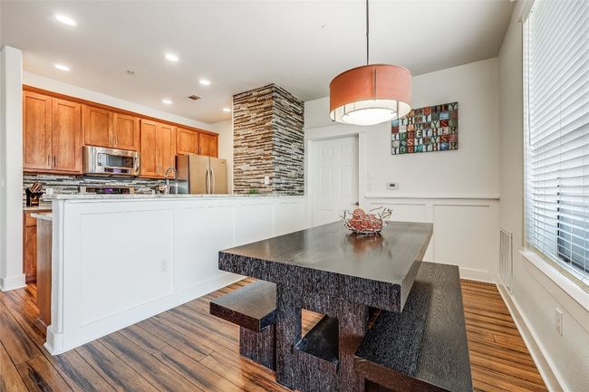 Kitchen with dark wood-style flooring, a decorative wall, appliances with stainless steel finishes, brown cabinets, and wainscoting | Image 6