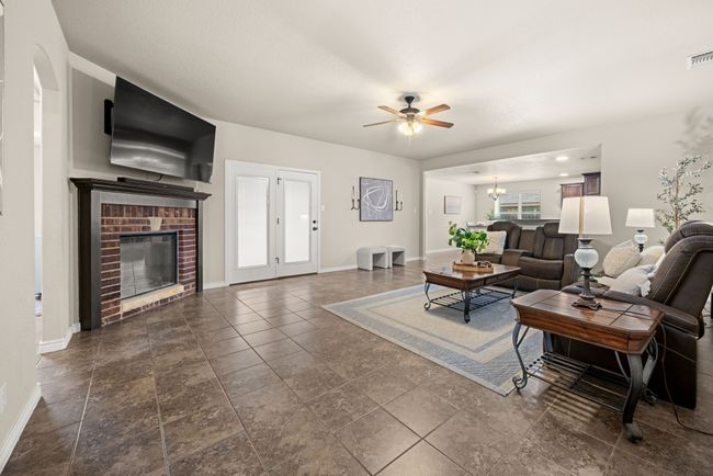 Living area featuring a ceiling fan, a brick fireplace, and a chandelier | Image 6