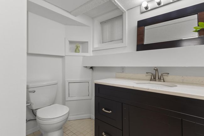 Lower Level 3/4 Bathroom features a modern vanity cabinet with quartz top, glass shower door and tile surround and flooring | Image 33