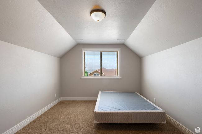 Unfurnished bedroom featuring carpet floors, lofted ceiling, and a textured ceiling | Image 23