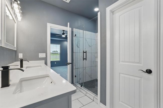 Bathroom featuring a ceiling fan, tile finish floor, a sink, and a marble finish shower | Image 15