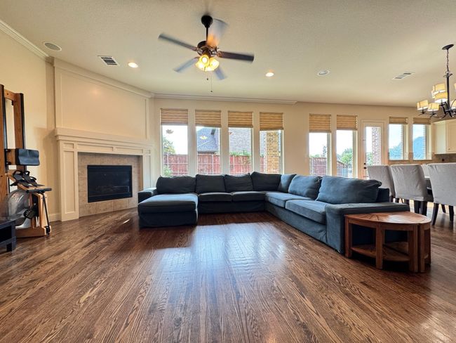 Living room with a chandelier, dark wood-style floors, crown molding, ceiling fan, and recessed lighting | Image 4