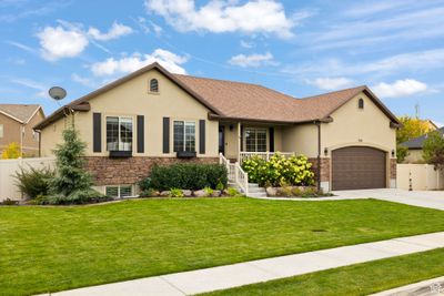 Ranch-style home with covered porch, a front yard, and a garage | Image 2