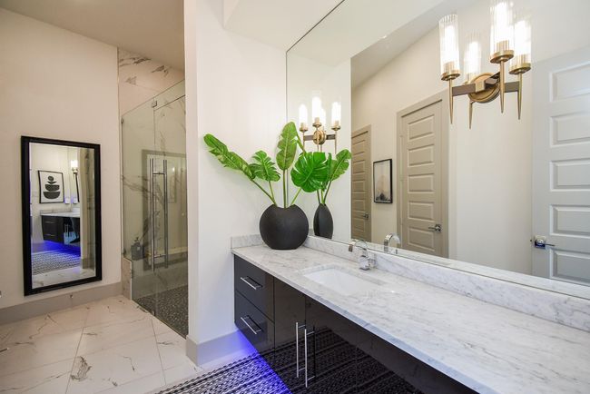 Luxurious secondary bathroom with huge frameless glass shower, oversized Carrarra white marble countertop and custom sconces. | Image 35