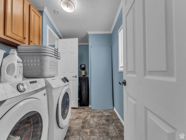 Clothes washing area with cabinet space, ornamental molding, washing machine and clothes dryer, baseboards, and a textured ceiling | Image 15