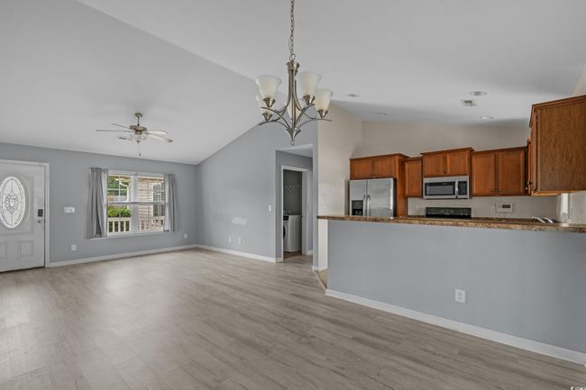Kitchen with appliances with stainless steel finishes, a ceiling fan, brown cabinets, vaulted ceiling, and light wood finished floors | Image 17