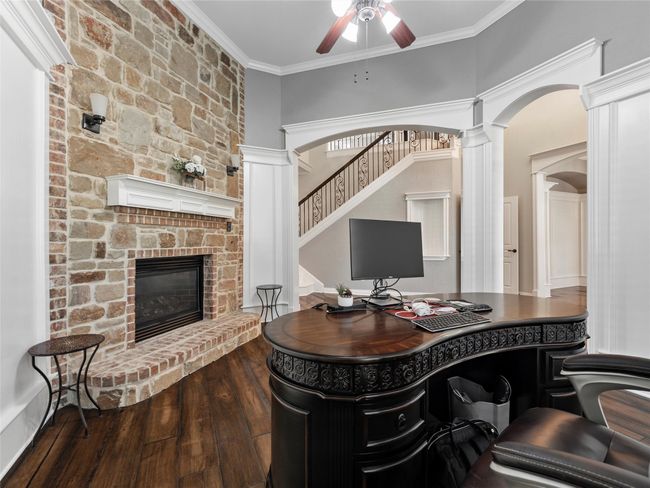 Office with a fireplace, a ceiling fan, wood finished floors, decorative columns, and arched walkways | Image 14