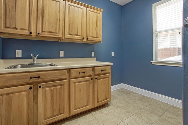 Kitchen featuring a sink, light countertops, baseboards, and light tile patterned floors | Image 34
