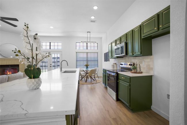 Kitchen featuring green cabinetry, stainless steel appliances, light wood-style floors, backsplash, and recessed lighting | Image 10