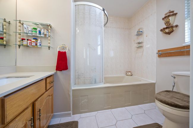 Bathroom featuring washtub / shower combination, vanity, toilet, and tile patterned flooring | Image 26