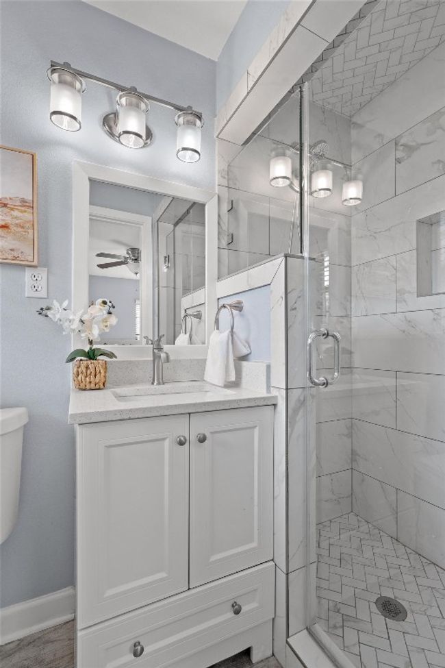 Full bathroom featuring a shower stall, baseboards, toilet, vanity, and a ceiling fan | Image 21