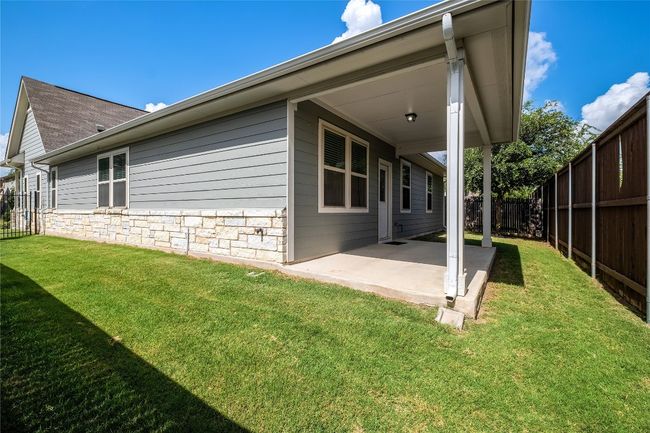 Rear view of house featuring a fenced backyard, a patio, stone siding, and roof with shingles | Image 6