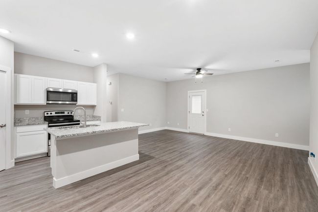 Kitchen with stainless steel appliances, a sink, ceiling fan, light wood-style flooring, and baseboards | Image 10