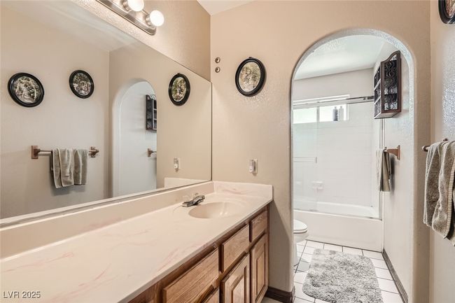 Bathroom featuring toilet, shower / bath combination with glass door, vanity, and tile patterned floors | Image 22
