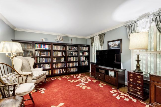 Sitting room with crown molding, wood finished floors, and wall of books | Image 4
