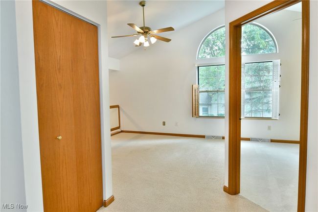 Empty room with carpet floors, a ceiling fan, and lofted ceiling | Image 23