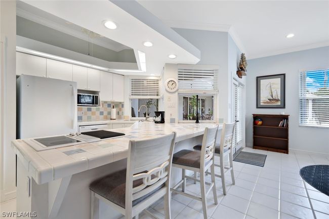 Kitchen with white cabinets, stainless steel microwave, a wealth of natural light, backsplash, and white fridge | Image 22