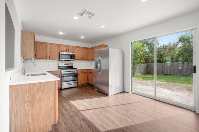 Kitchen featuring light countertops, a sink, stainless steel appliances, visible vents, and decorative backsplash | Image 8