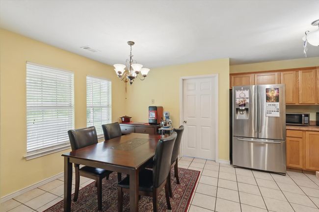 Dining area featuring visible vents, a notable chandelier, light tile patterned flooring, and baseboards | Image 17